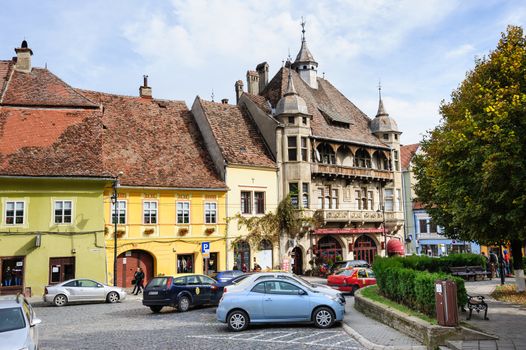 Sighisoara, Romania - October 19th, 2016: View of modern streets with people and cars in historic center of Sighisoara, Transylvania region, Romania