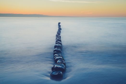Breakwaters in the Baltic sea over the sunset in summer