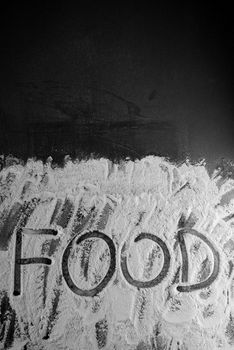 Word food written with flour on black background.