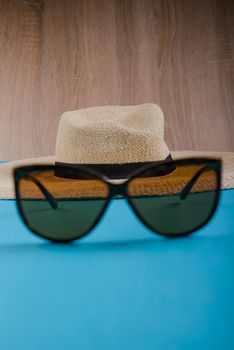 Straw hat and sunglasses on blue background. beach equipment.