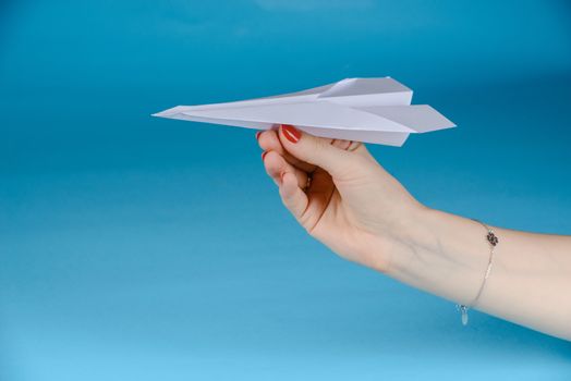 Paper plane in female hand on a blue background