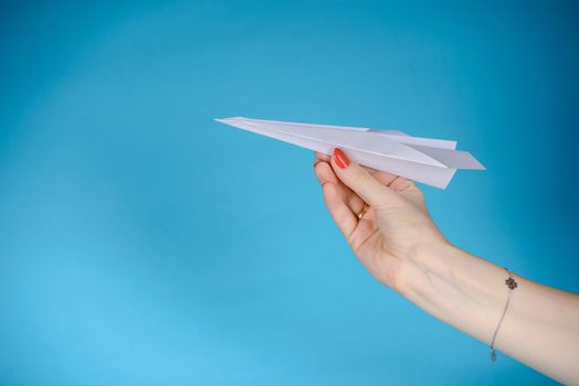 Paper plane in female hand on a blue background