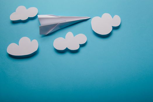 Paper plane in female hand on a blue background with clouds
