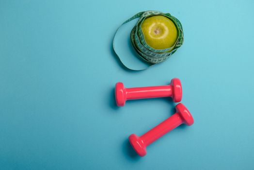 Pair of pink 1 kg dumbbells on blue background and water bottle