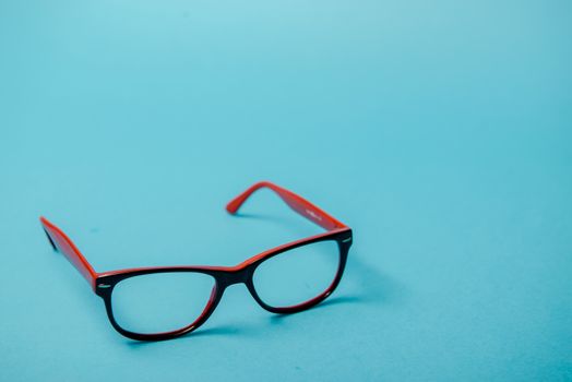 pair of red plastic-rimmed eyeglasses on a blue background