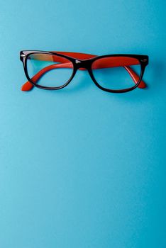 pair of red plastic-rimmed eyeglasses on a blue background