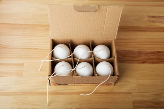 Decorative Handmade candles in the shape of eggs ready for painting and decorating for the holiday. White candles on wood background with copyspace. Candle lit. Happy Easter