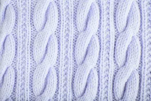 Sweater or scarf texture large knitting. Knitted jersey background with a relief pattern. Braids in knitting. Wool hand-knitted or machine knitting pattern. Fabric Background.