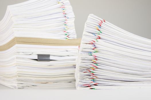 Pile overload paper of receipt and report with colorful paperclip have blur pile document and brown envelope as background on white table.