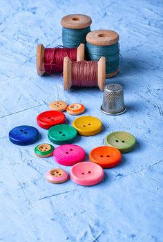 Set of buttons and thread on bright blue background