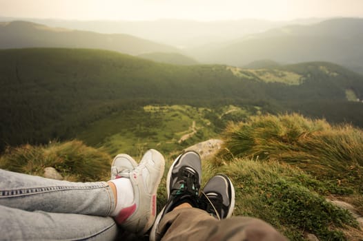 Point of view of two persons sitting on top of the mountain enjoying the scenery.