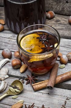 glass of mulled wine with almonds,cinnamon and anise on background of carafe of wine