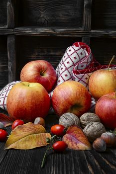 Harvest of red apples and nuts on dark wooden background