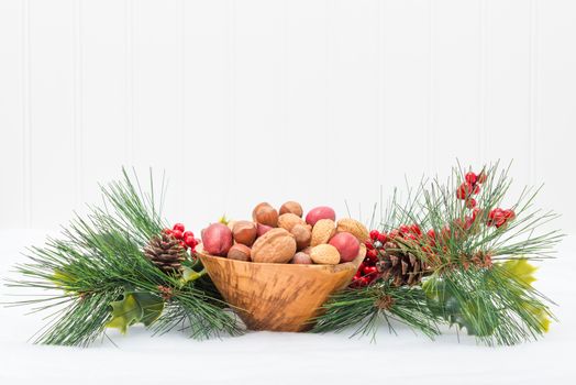 Wooden bowl of mixed nuts surrounded by a festive garland.