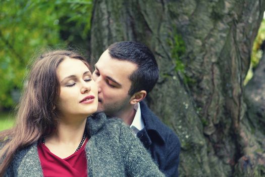 sad young couple in autumn park together faces close