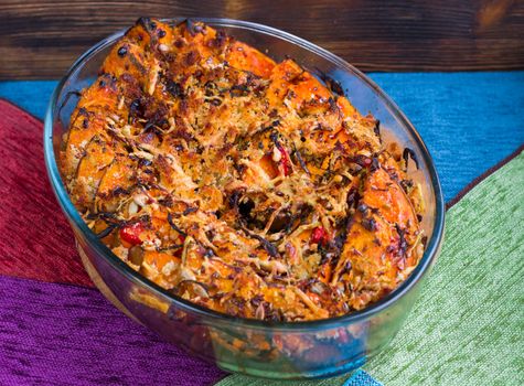 Vegetarian dish of orange pumkin, mixed vegetables, herbs and cheese baked in oven