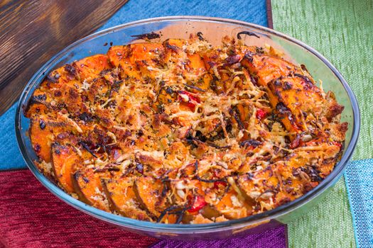 Vegetarian dish of orange pumkin, mixed vegetables, herbs and cheese baked in oven