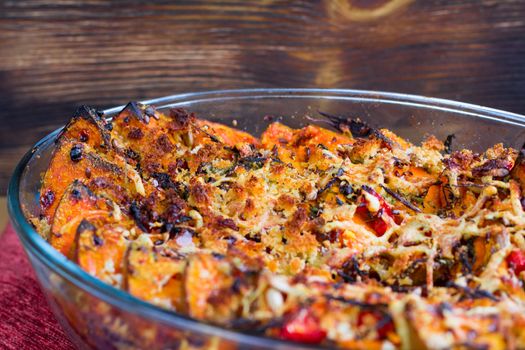 Vegetarian dish of orange pumkin, mixed vegetables, herbs and cheese baked in oven