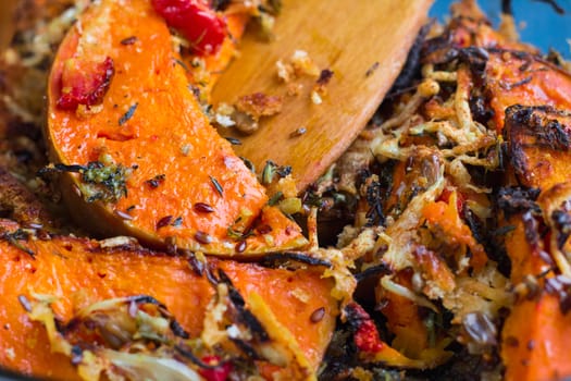 Vegetarian baked dish close-up with orange pumkin, mixed vegetables, herbs, cheese