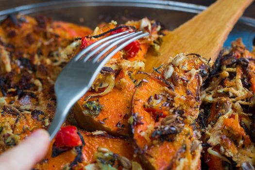 Trying vegetarian baked orange pumkin, mixed vegetables, herbs and cheese with folk
