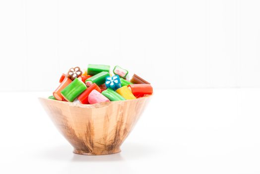 Colorful soft chewy candy in a wooden bowl with ample copy space.