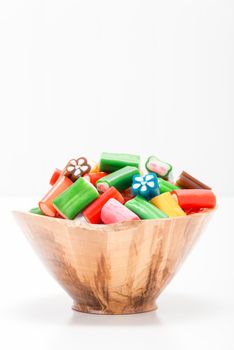 Wooden bowl filled with soft chewy colorful candies.