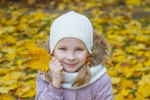 Cute girl with autumn leaf over yellow back