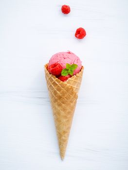 Raspberry ice cream in cone with fresh raspberry and peppermint leaves setup on white wood background  . Summer and Sweet concept flat lay.