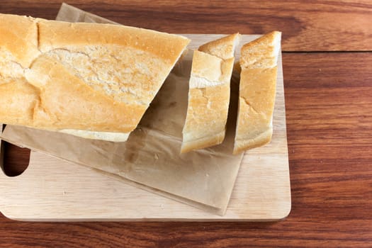 French bread baguette cut on brown paper with wooden board. Flat Lay for food