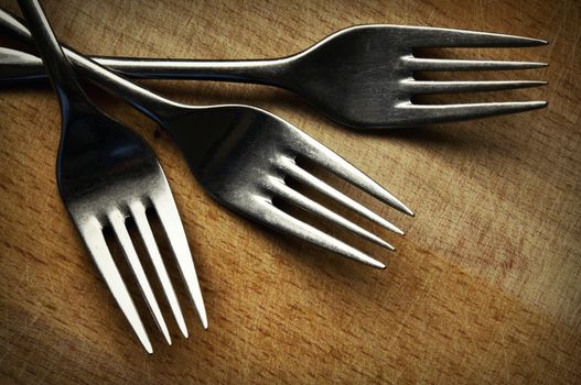 retro background Three stainless steel fork on the kitchen board