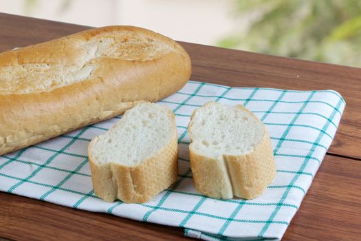 French bread baguette cut on white fabric with wooden board