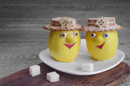 Lemons with sugar on a white plate and brown Board. Grey wooden background.