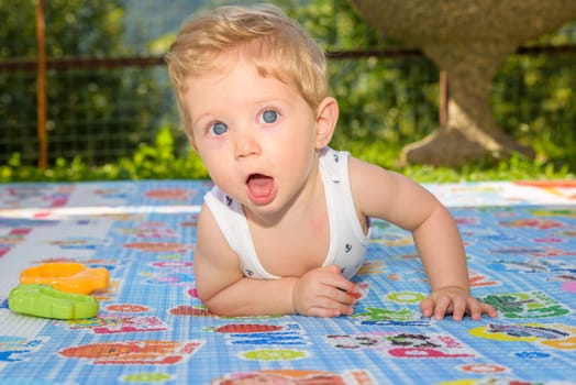 Beautiful baby boy eight month old crawling in the garden,close up.