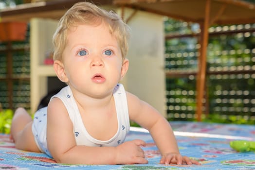 Beautiful baby boy eight month old crawling in the garden,close up.