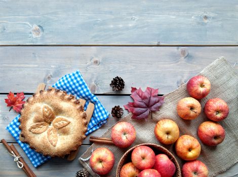 Apple pie with fruit ingredients and cinammon sticks on a wooden table 