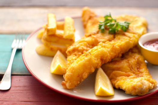 Deep fried battered fish on a plate with chips close up