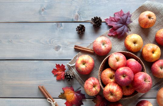 Autumn leaves, apples over a wooden background with space 