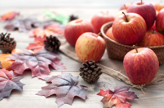 Autumn leaves with apples over a wooden background