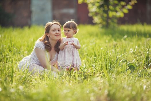 Happy mother sitting with daughter in park outdoors