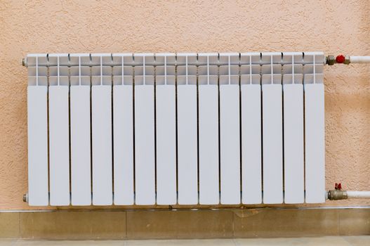 White new radiator on a pink wall