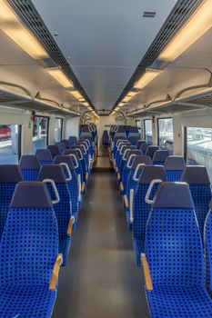 Image inside an empty german train wagon with the modern blue chairs disposed on two rows