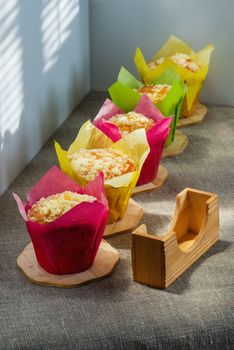 Muffins of different color on wooden supports on a cloth from rough fabric