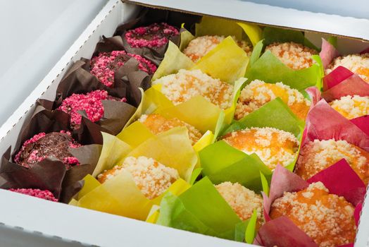 The muffins of different color packed into color paper and into a cardboard box