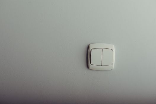 White plastic light switch on a gray wall