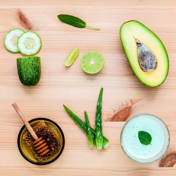 Homemade skin care and body scrub with natural ingredients avocado ,aloe vera ,cucumber and honey set up on wooden background.
