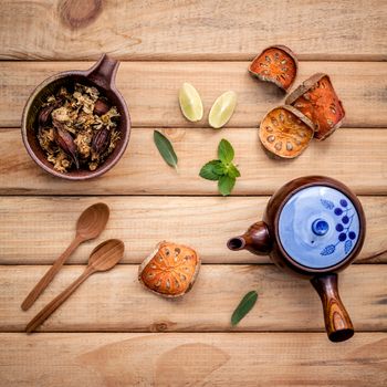 Herbal tea pot with fresh herbs sage ,peppermint ,dried indian bael, honey, lime and lemon on rustic wooden background.