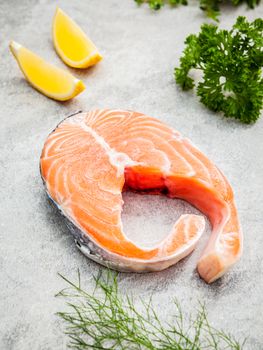 Fresh salmon fillet slice on dark stone background with herbs fennel ,sage ,rosemary thyme,parsley and lemon propose  for cooking . Healthy food concept.