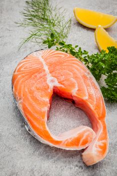 Fresh salmon fillet slice on dark stone background with fennel and lemon propose for cooking . Healthy food concept.