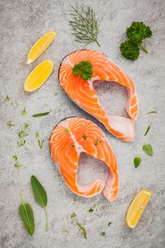 Fresh salmon fillet slice on dark stone background with herbs fennel ,sage ,rosemary thyme,parsley and lemon propose  for cooking . Healthy food concept.