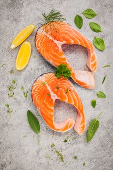 Fresh salmon fillet slice on dark stone background with herbs fennel ,sage ,rosemary thyme,parsley and lemon propose  for cooking . Healthy food concept.